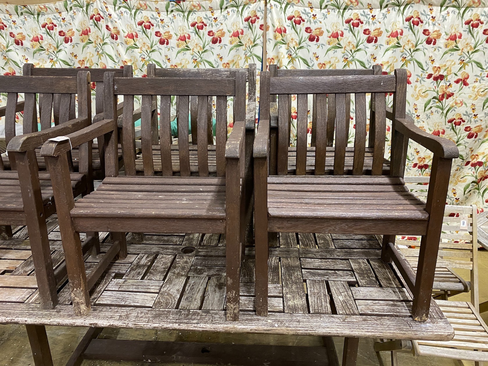 A rectangular weathered teak garden table, length 212cm, width 110cm, height 74cm and six elbow chairs by Alexander Rose